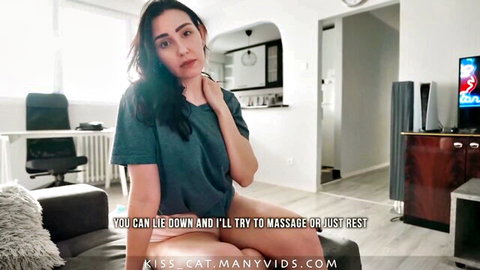 Brunette woman in gray top offers relaxing massage on couch, teasing pose