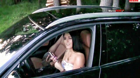 Busty brunette MILF smiling on phone in car showing deep cleavage tease