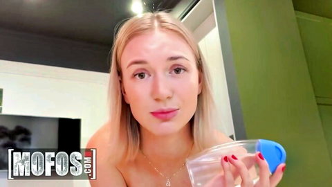 Blonde babe with perky tits topless holding clear glass with blue cap