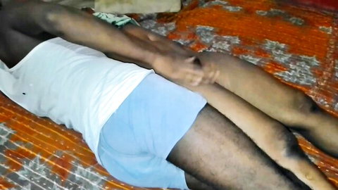 Desi old man in white tank and blue shorts, legs spread on mat during fight scene