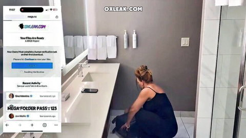 Janet Mason squatting in black dress in hotel bathroom scene