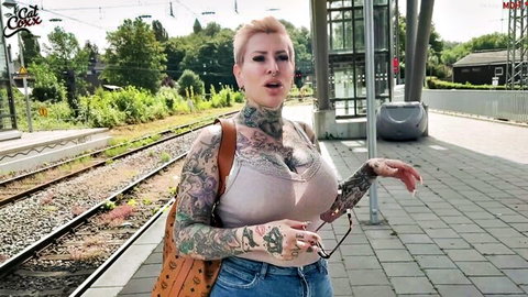 Tattooed blonde MILF with big tits in lace bra posing at outdoor train station