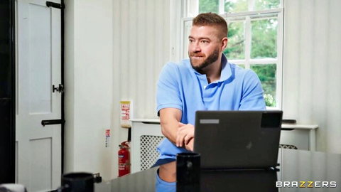 Xander Corvus exposes big cock while leaning on laptop in blue polo shirt