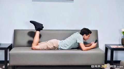 Young man lounging on couch in teasing Brazzers scene with Ellie Nova, Cherie DeVille