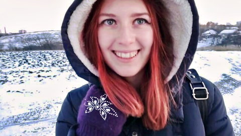 Smiling Russian redhead in winter jacket and gloves outdoors in snow