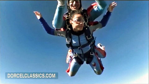 Hot brunette tandem skydiving with stud over airfield, thrilling freefall adventure