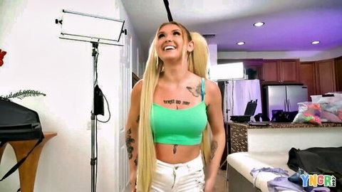 Skinny tattooed blonde babe with small tits smiles in tight green 'TITS' crop top and white pants