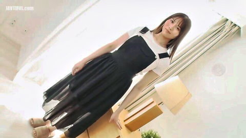 Cute Asian babe in sheer black overall dress smiling teasingly from low angle