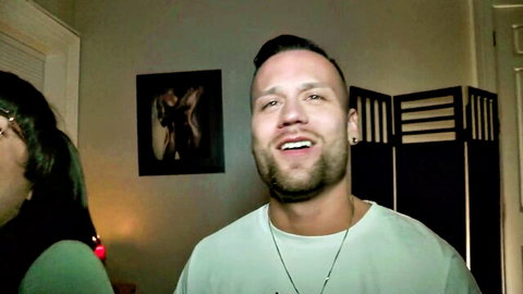 Smiling bearded guy in green shirt with sexy brunette girlfriend in bedroom POV