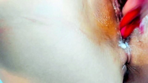 Close-up of shaved pussy oozing thick creampie cum from spread labia with red nailed fingers