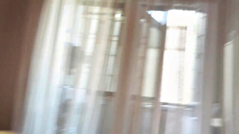 Soft light filtering through billowing sheer white curtains in a warm brown room