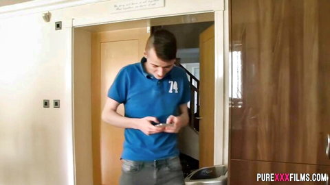 Young Caucasian guy in blue polo shirt holds phone in hallway doorway