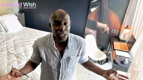 Bald black man in open shirt gestures openly in bedroom with Wild Wish overlay