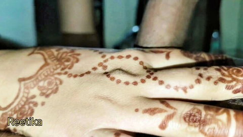 Closeup of intricate mehndi henna designs on Indian woman's hands and man's arm