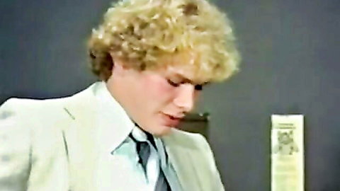 Vintage blonde man in cream suit and tie speaking into mic closeup