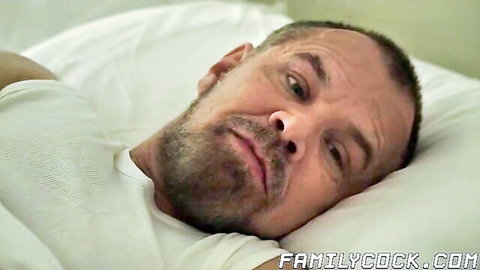 Bearded DILF lying in white tank top on bed with intense morning gaze