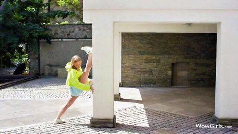 Skinny blonde teen flexes high leg split against pillar in tight yellow shorts teasing pussy outline