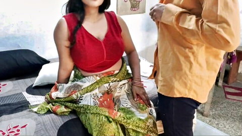Indian babe in red low-cut blouse showing big tits cleavage as man undresses shirt beside her on bed