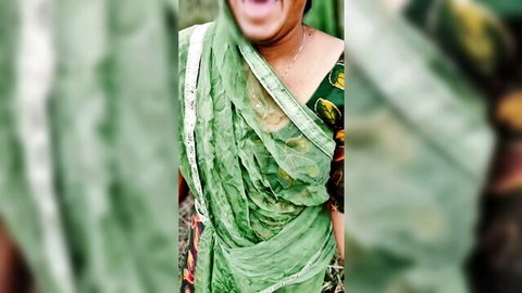 Smiling Indian bhabhi in green saree poses seductively outdoors