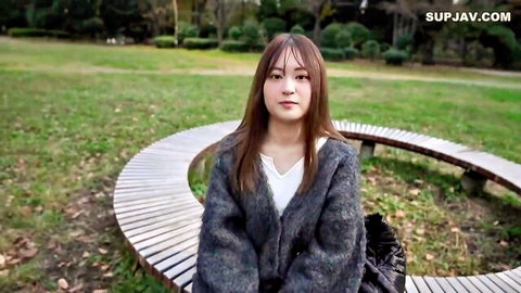 Cute Asian woman in gray cardigan sits on bench outdoors, JAV style