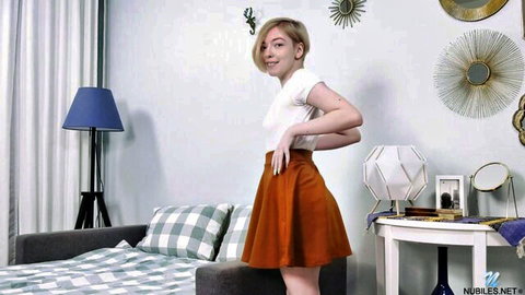 Smiling blonde teen with puffy nipples in tight white top and short skirt posing in knee socks
