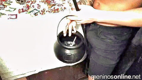 Woman pulls down dark pants exposing ass while fingering black Halloween cauldron pot sensually