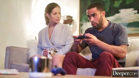 Katrina Jade in silky robe relaxing on couch with handsome black stud gaming