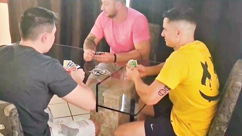 Four muscular tattooed guys in shirts and shorts playing poker at glass table