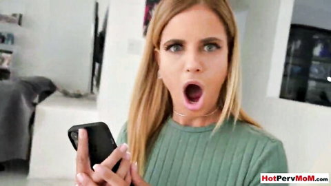 Blonde MILF Jesse Pony surprised holding phone in green top, big tits visible