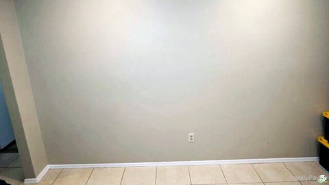 Empty beige room corner with yellow storage bins and electrical outlet before playboy action