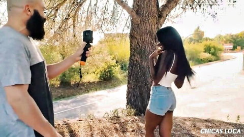 Hot black babe with big juicy ass in tiny denim shorts looks back while guy films her outdoors