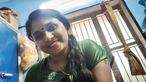 Smiling Indian housewife in shiny green blouse smiling seductively at home