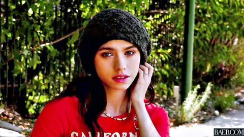 Seductive young babe in red California top and beanie with pouty lips teasing outdoors