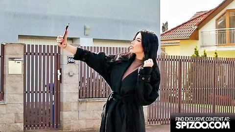 Naughty brunette teases deep cleavage in open black coat outdoor selfie