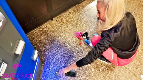 Candy Suck blonde model squatting in pink leggings at blue-lit machine, big tits tease