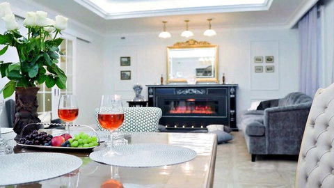 Elegant romantic dinner table with rosé wine glasses grapes fruit and white roses by luxury fireplace