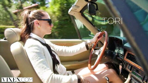 Brunette Tori driving convertible car with thighs exposed in sexy white blazer
