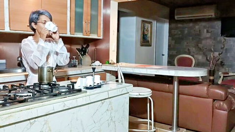 MILF in sheer white blouse sips coffee in kitchen teasing small tits