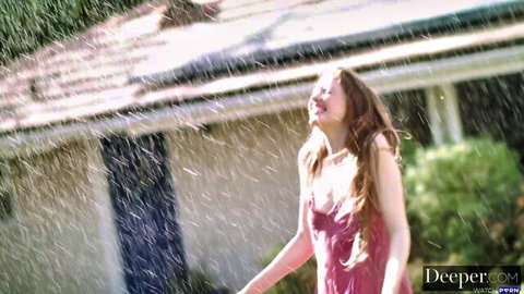 Brunette teen smiling happily in wet clinging pink dress outdoors