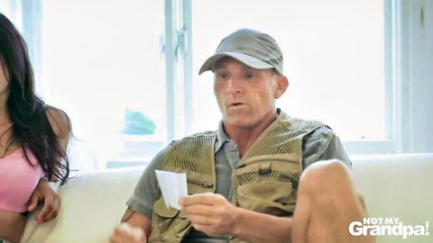 Skinny tanned Latina in pink top eyes shocked older man holding cash on couch