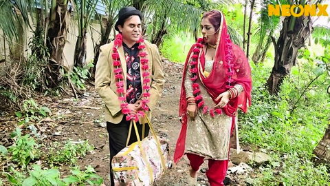 Desi couple in wedding garlands walking outdoors in traditional attire