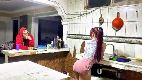 Latina with long ponytail bends over kitchen sink in tight pink shorts showing juicy ass to guy in red hoodie