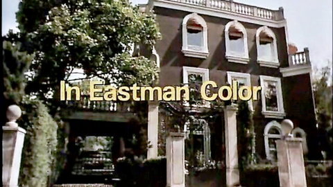 Vintage mansion exterior with arched windows trees and pillars in Eastman Color film credit overlay