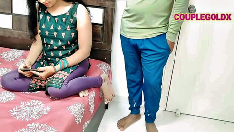 Sexy Indian wife in tight purple leggings sits on bed checking phone while husband stands nearby amateur homemade