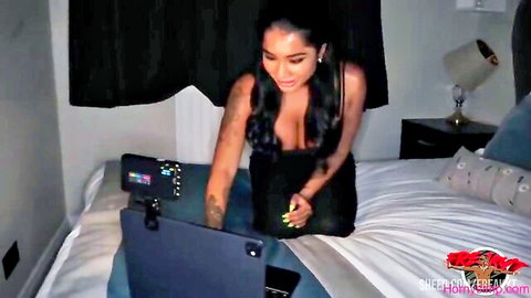 Yasmina Khan in low-cut black dress, seductive pose on bed