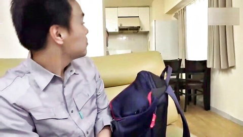Asian man in casual shirt glances back in apartment setup for kinky threesome