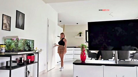 Blonde MILF with big tits in skimpy black crop top and frilly mini skirt grabbing kitchen door handle