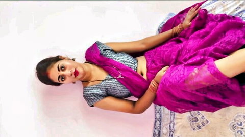 Seductive Indian housewife in pink saree lying on bed exposing midriff and cleavage