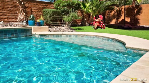 Busty woman in red bikini bottoms spreads legs wide exposing pussy by poolside