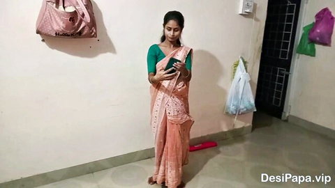Indian village teen in pink saree and green blouse, standing barefoot holding phone